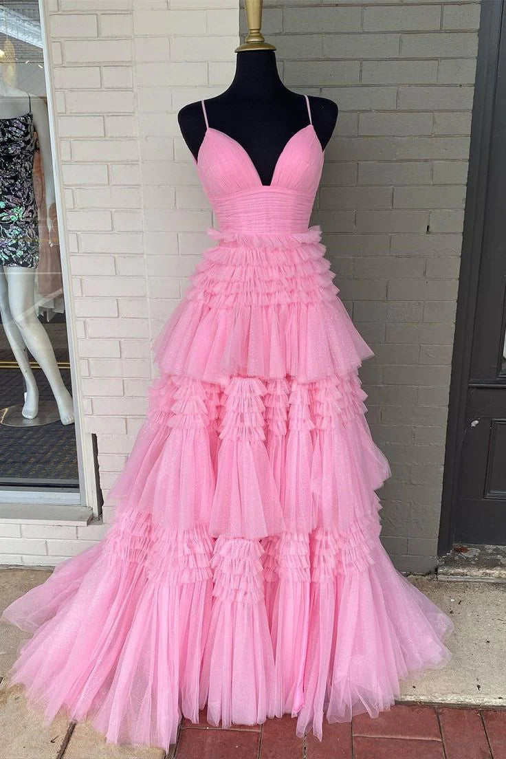 Woman in a pink layered tulle A-line V-neck evening dress, side view.