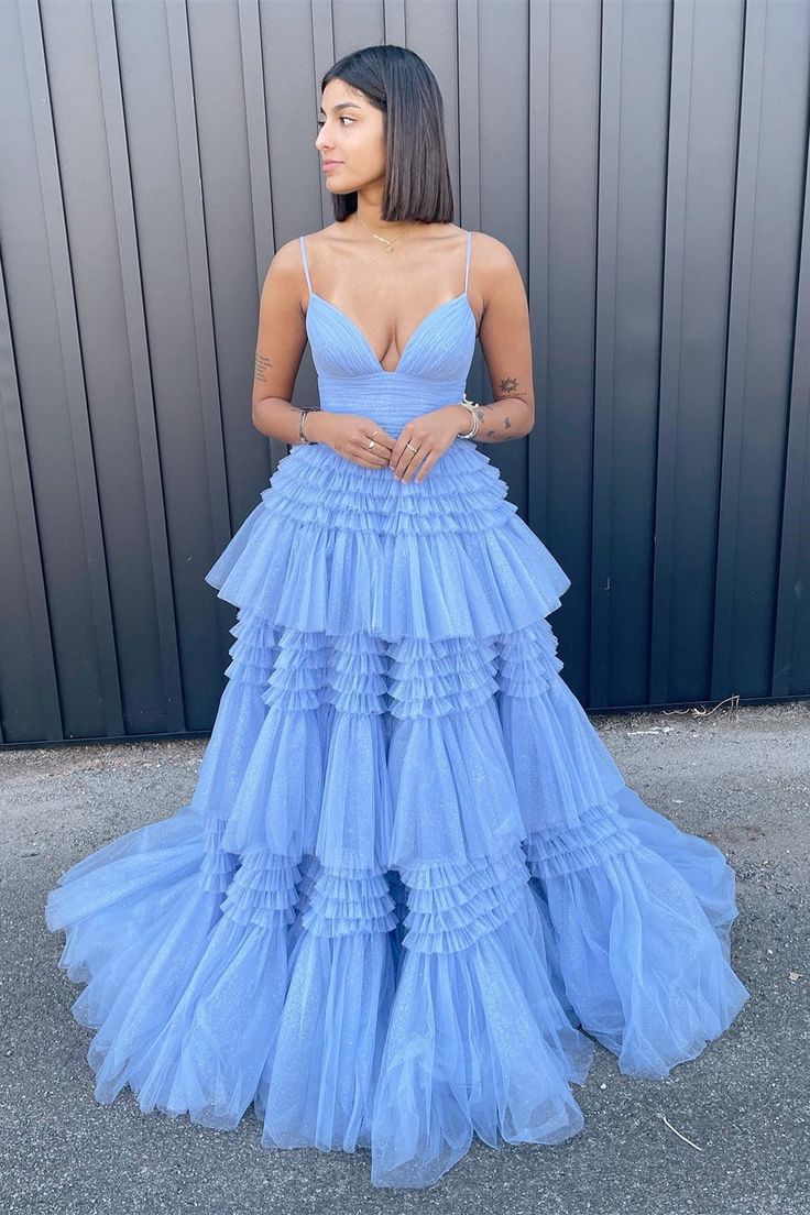 Woman in a dark blue layered tulle A-line V-neck evening dress, back view.