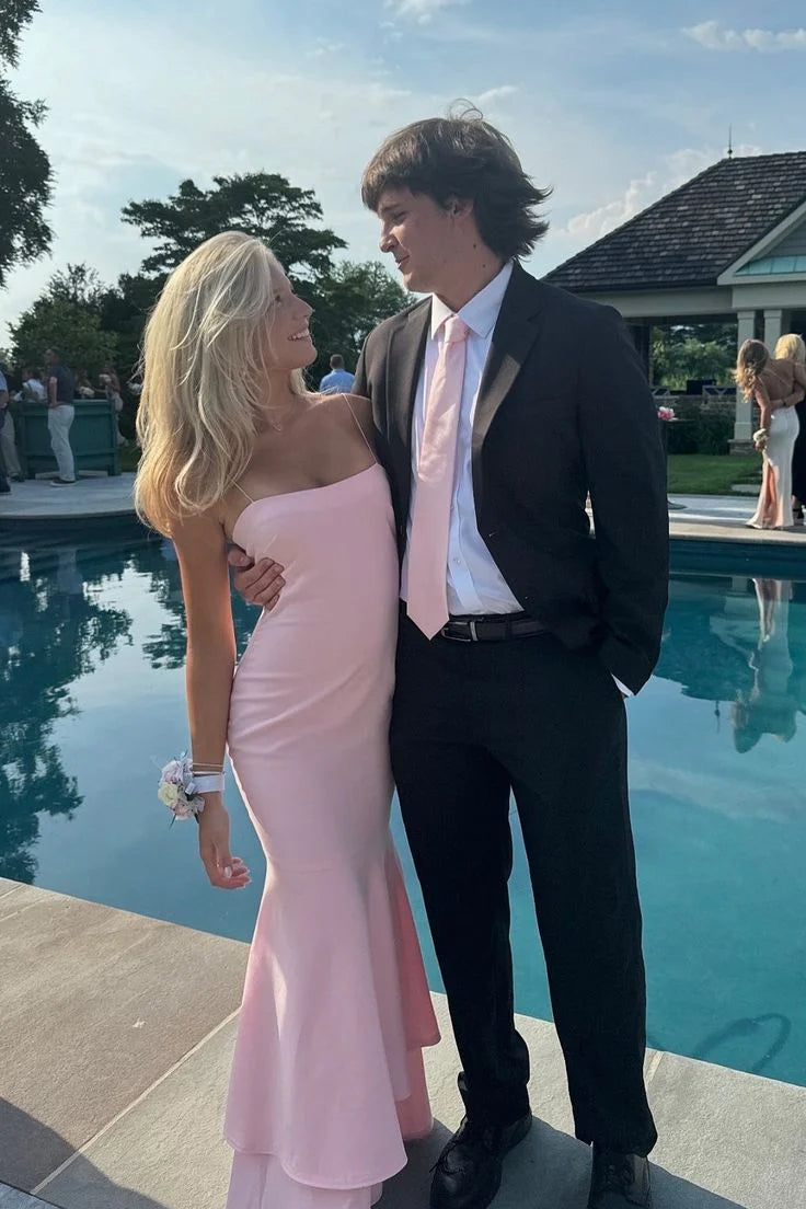 Woman wearing an elegant light pink mermaid prom dress with spaghetti straps.