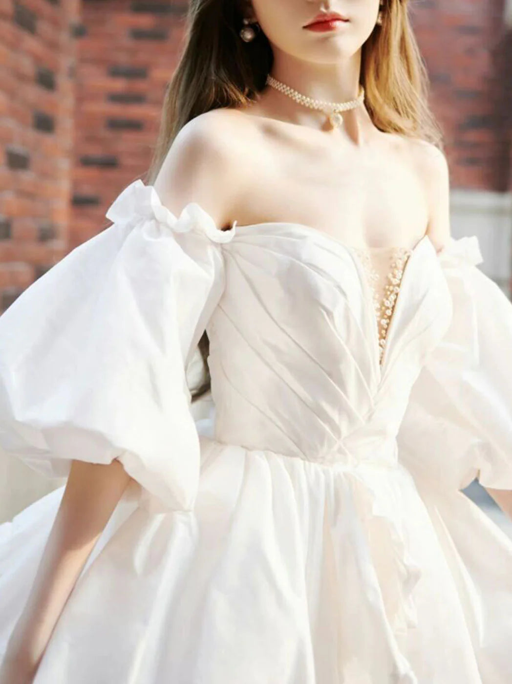 Front view of a woman wearing an elegant white long sleeve short taffeta prom dress.