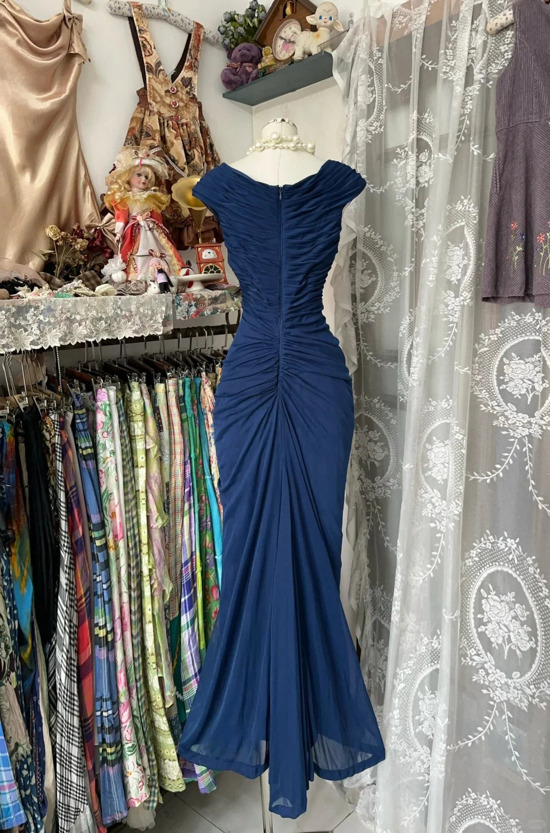 Side view of a woman in a sleeveless navy blue mermaid gown, showcasing the silhouette.