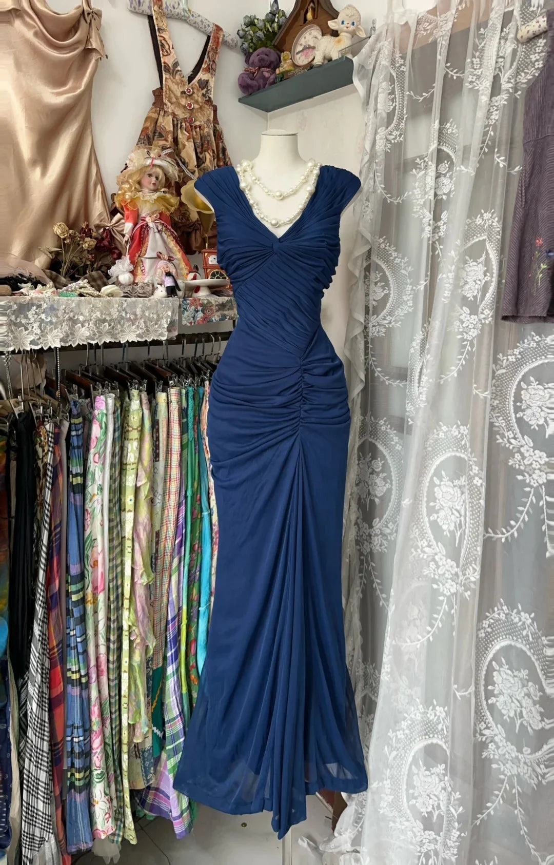 Front view of a woman wearing a sleek navy blue formal dress with a mermaid skirt.