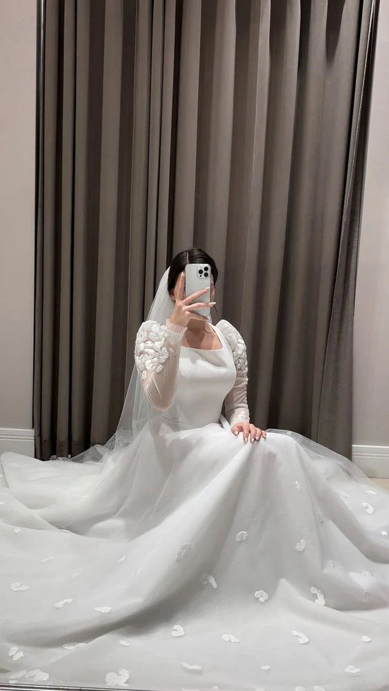 Close-up of the bodice and long tulle sleeves of a white modest wedding dress.