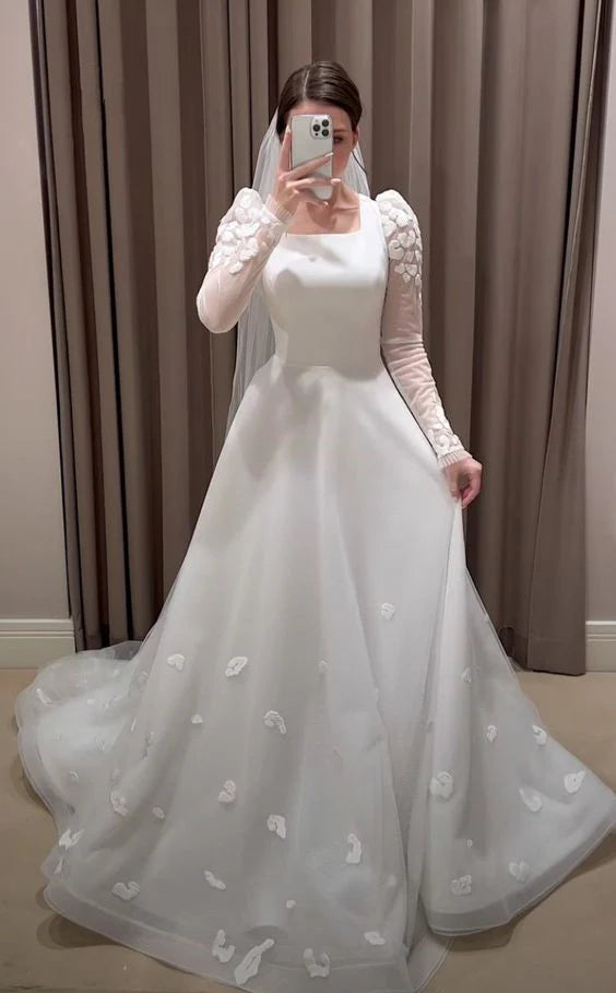 Back view of a white A-line wedding dress, showing the long sleeves and flowing skirt.