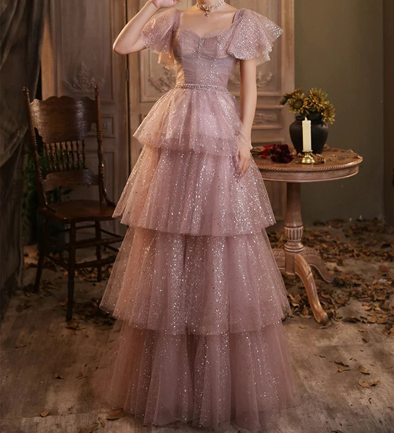 Full-length view of a pink waist-cinching multilayer floor-length evening dress.