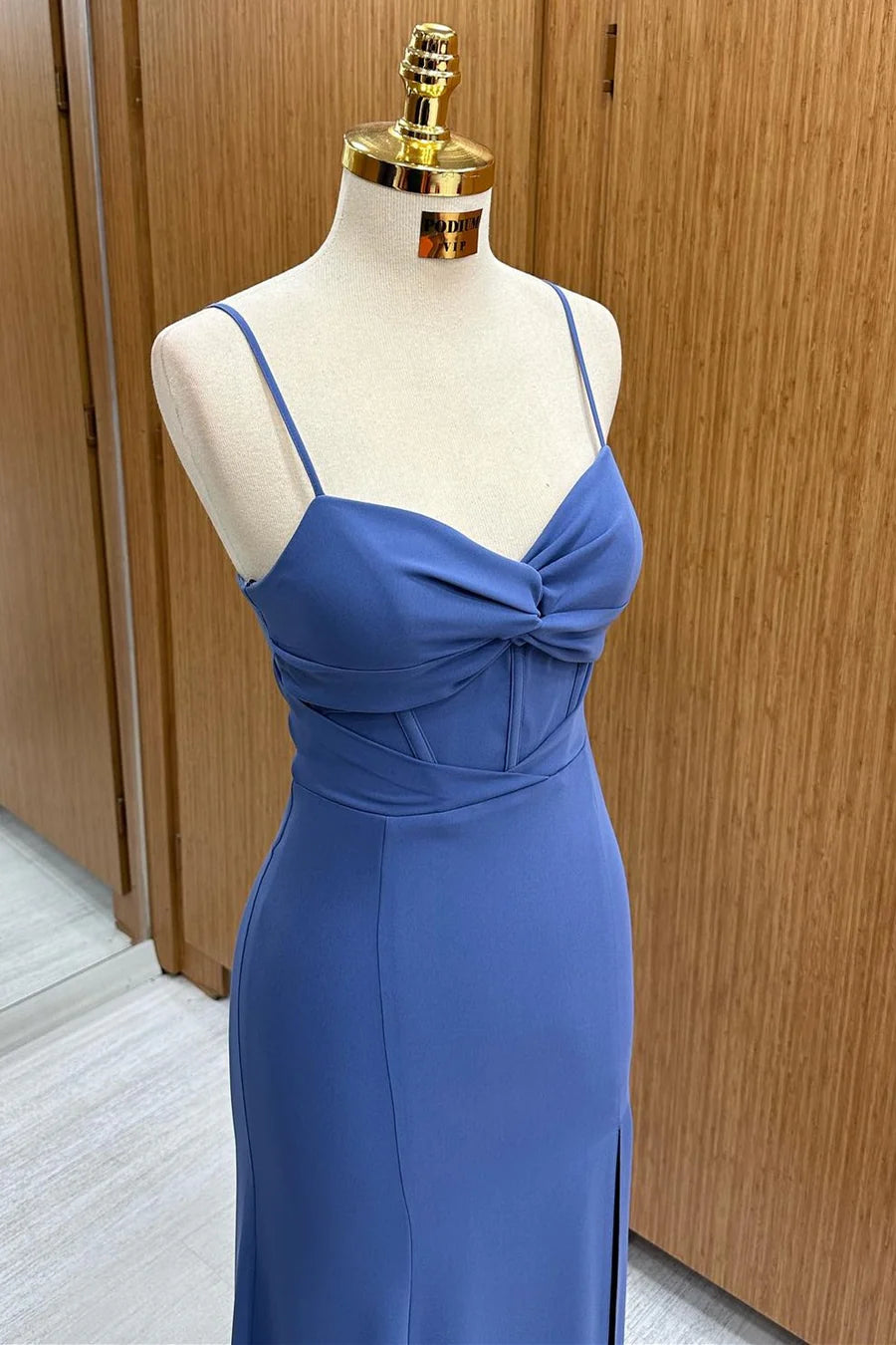 Model posing in a chic navy slim-fit formal gown, showcasing the twist-front detail and side slit.