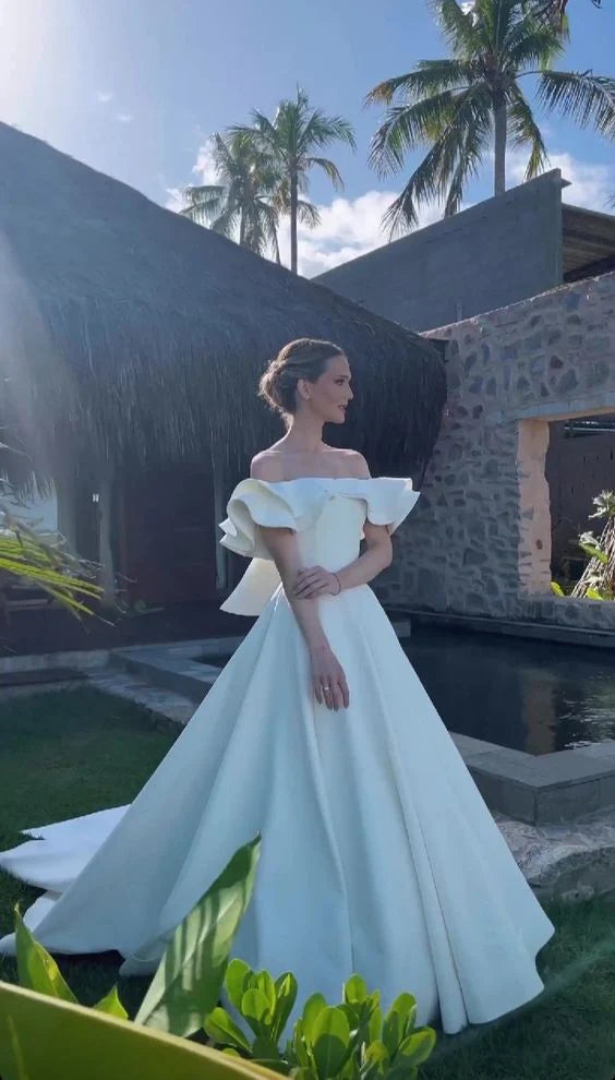 Back view of a model in a long off-shoulder satin wedding dress.