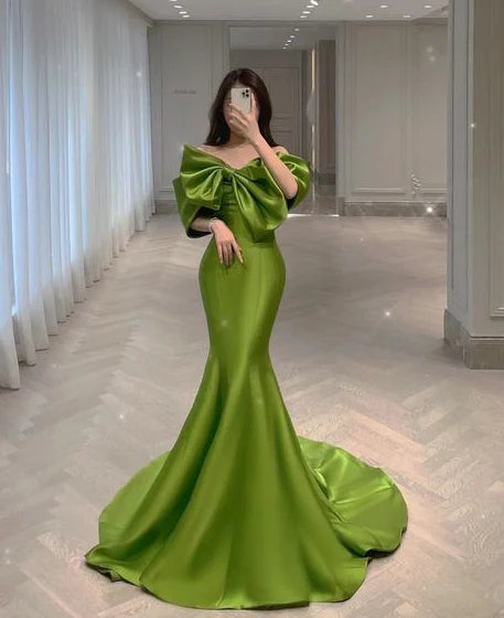 Woman wearing an elegant off-the-shoulder green mermaid evening gown.