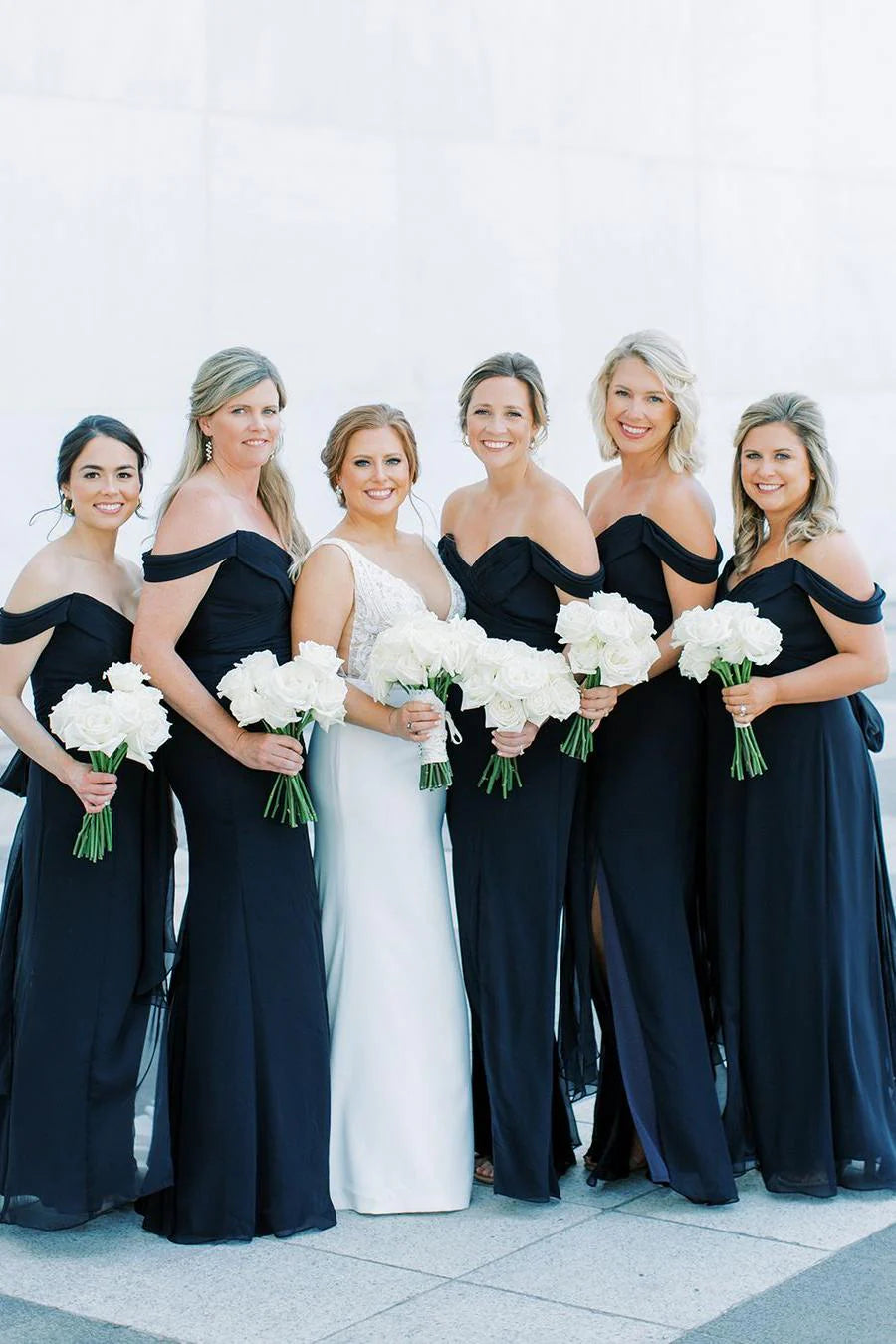 Side view of a model in a black off-shoulder V-neck long chiffon bridesmaid dress.