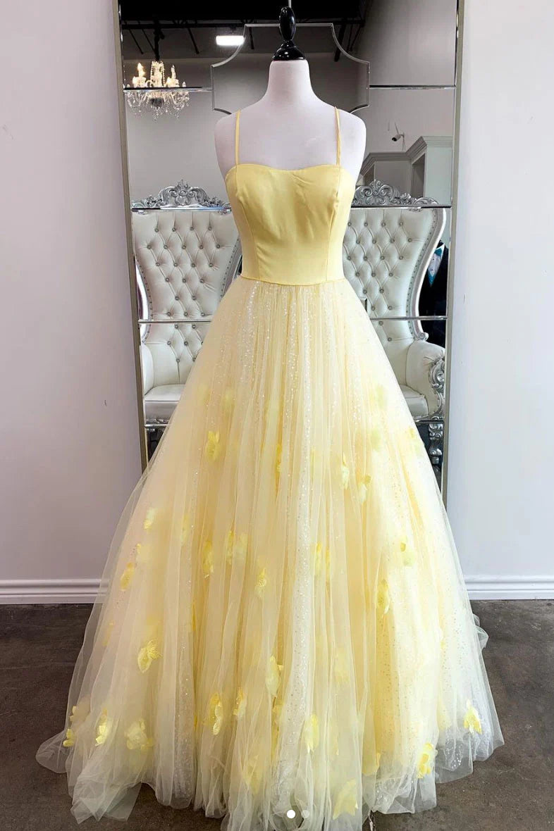 Woman wearing a long yellow off-shoulder prom dress with sequin bodice and flowing tulle skirt.