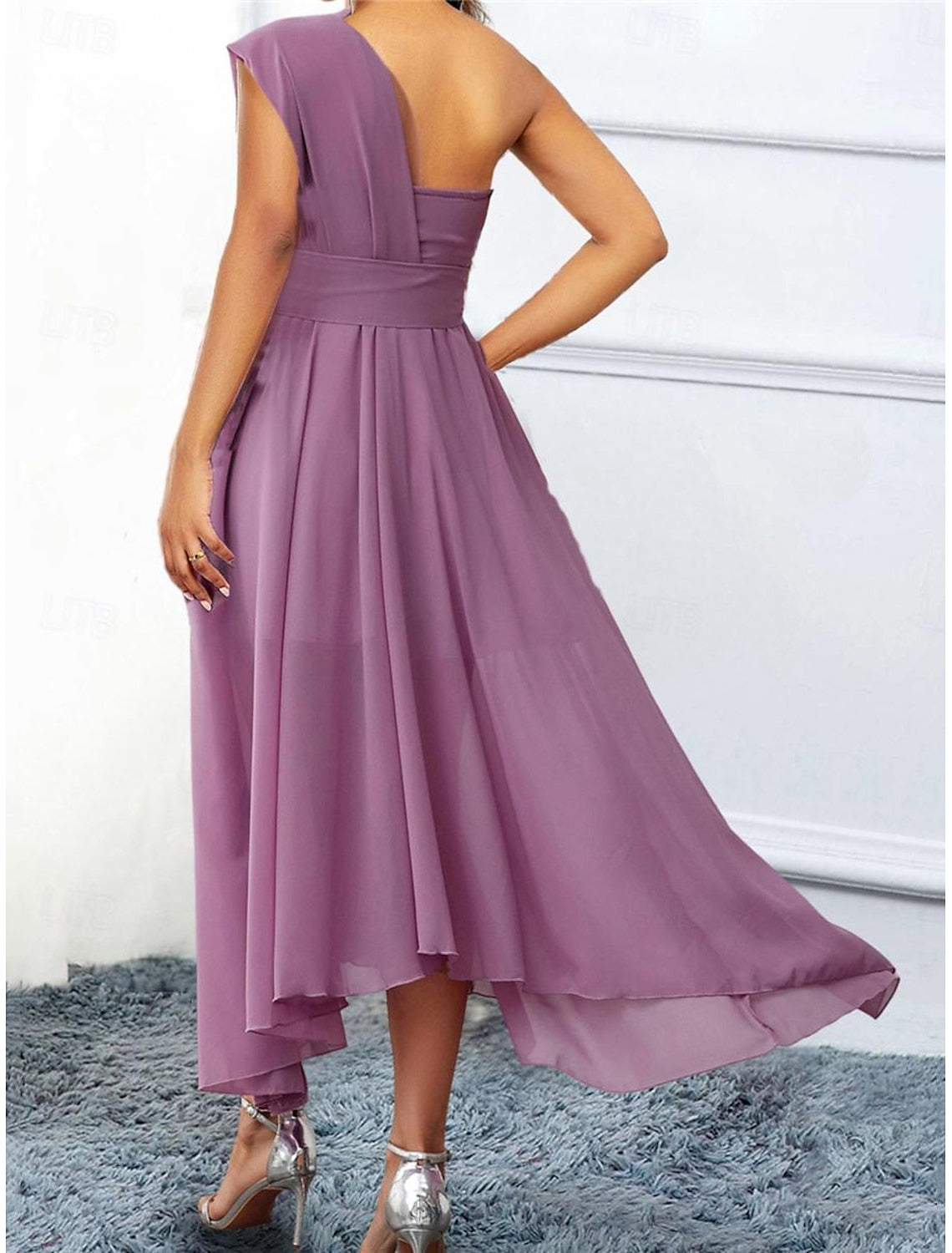 Back view of a woman in a light purple one-shoulder A-line chiffon dress.