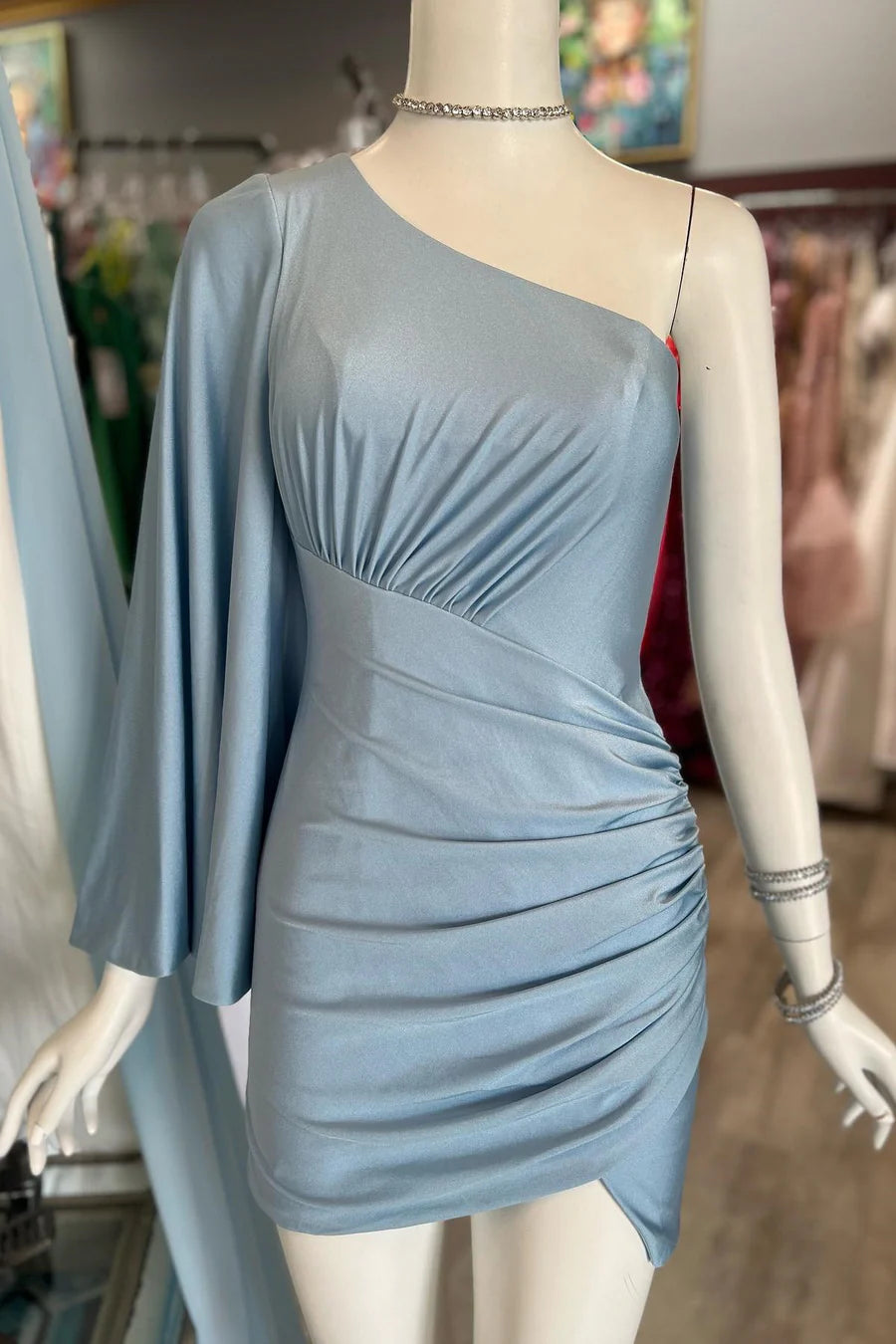 Model in a dusky blue one-shoulder bell sleeve short party dress, front view.