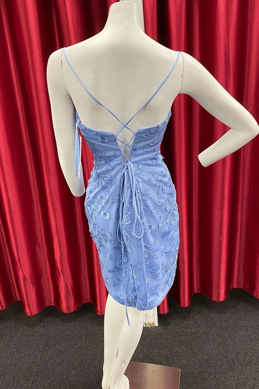 Back view of a woman wearing a periwinkle appliques mini party dress, showing the lace-up detail.