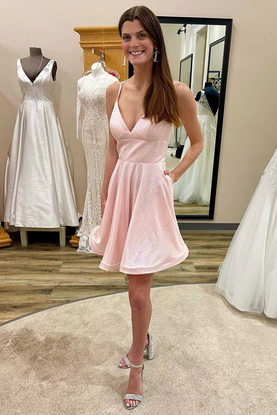 Model wearing an elegant pink A-line homecoming dress with a V-neckline, high waist, and side pockets.