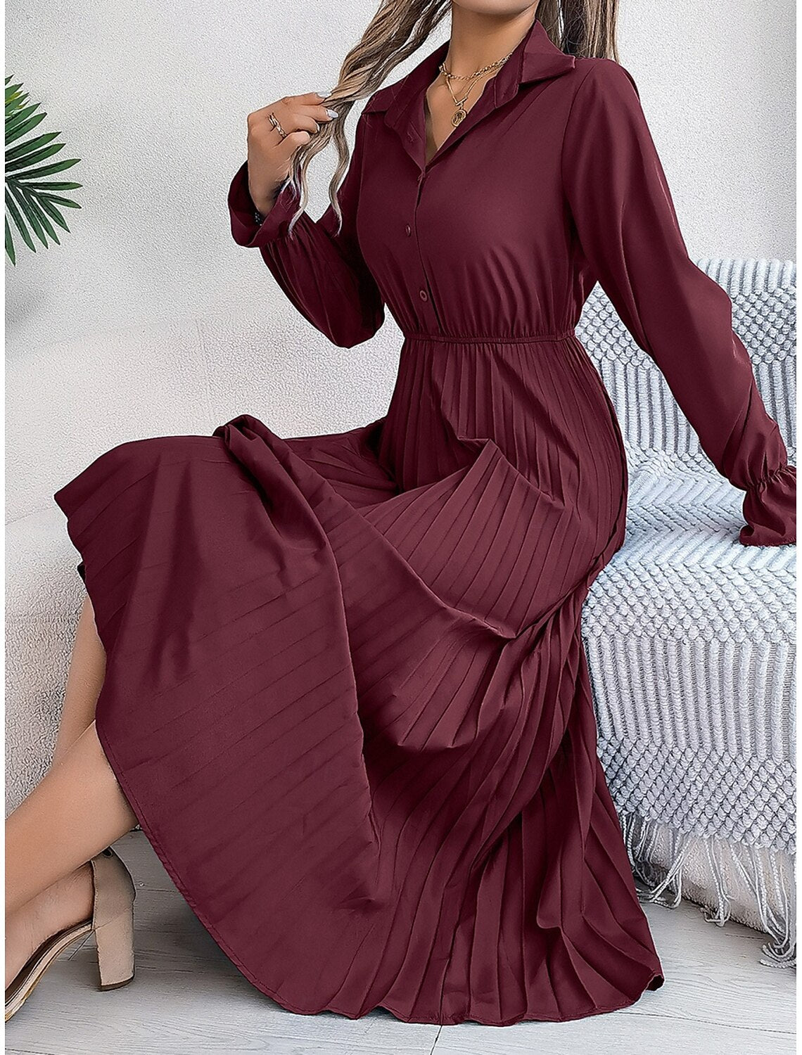Woman wearing a plain pleated A-line maxi dress with a shirt collar, front view.