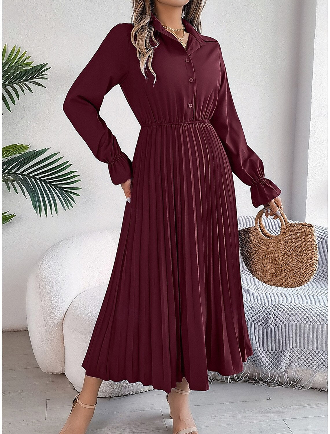 Woman in a plain pleated A-line maxi dress, back view, highlighting the flow of the skirt.