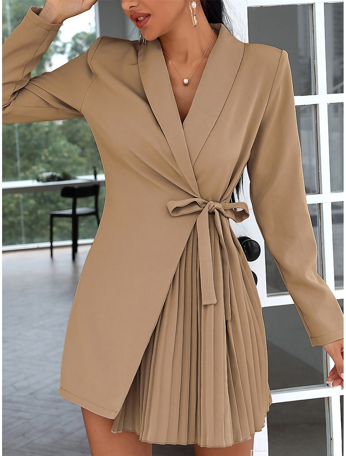 Woman modeling a black pleated long sleeve mini dress with a shirt collar and lace-up front.