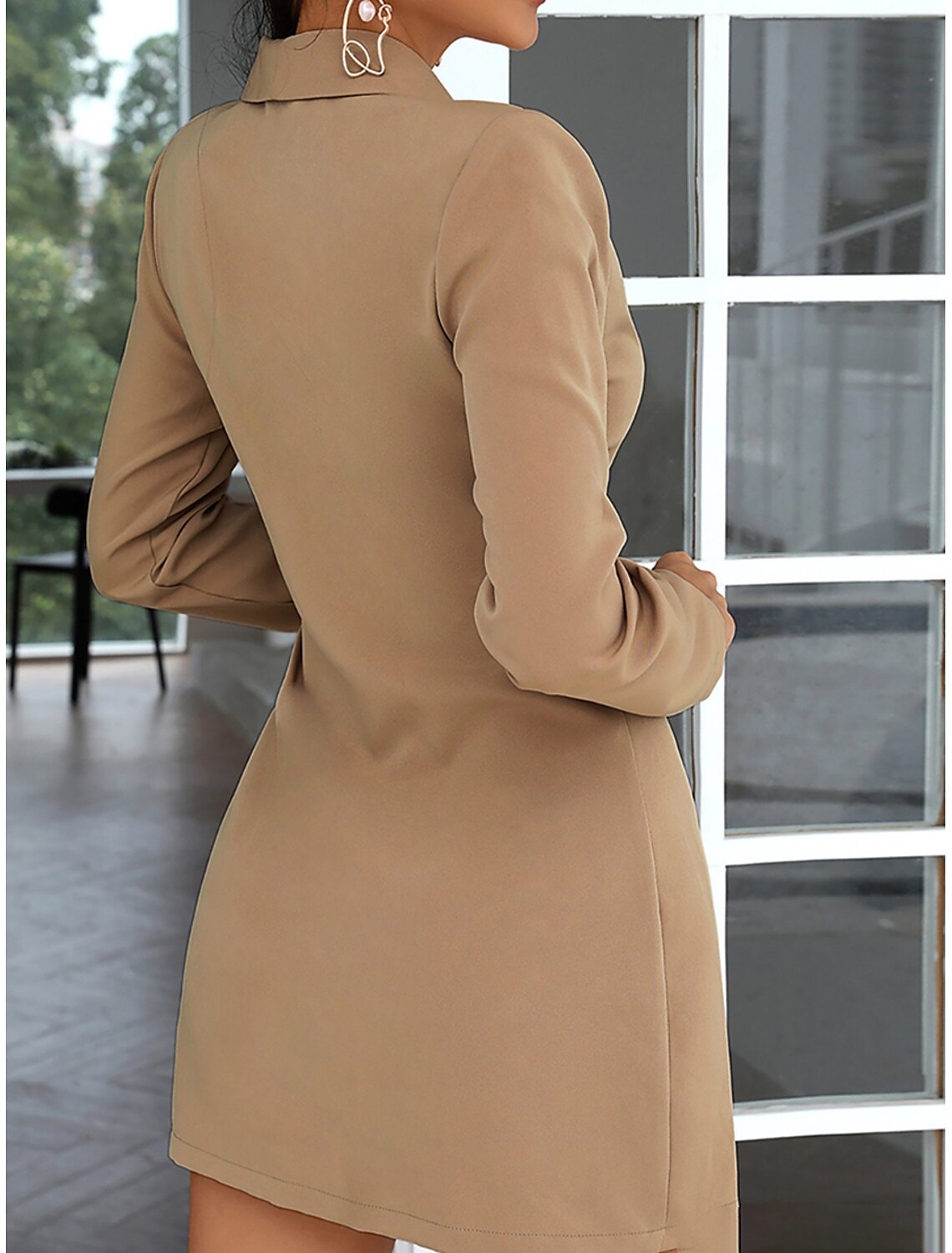Back view of a woman wearing a black pleated mini dress with long sleeves and a shirt collar.