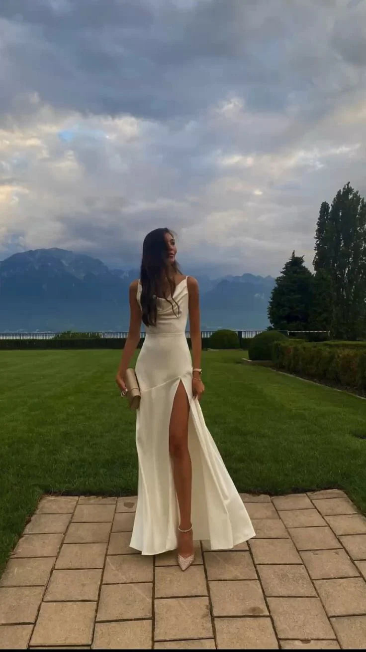 Model wearing a white pleated sleeveless ball gown with thin straps and a side slit.