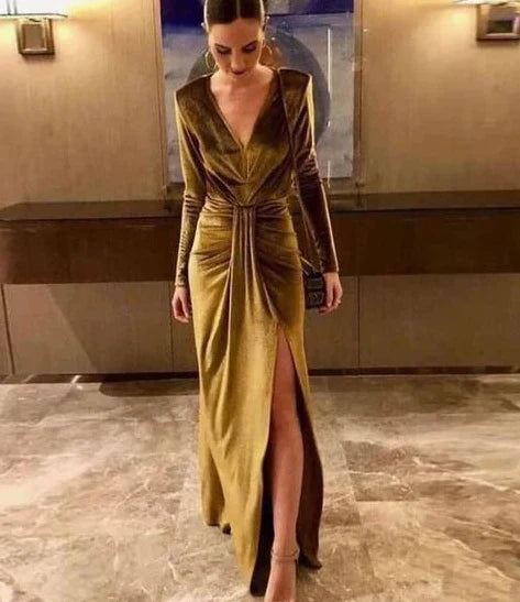 Woman wearing a dark velvet V-neck long sleeve ball gown with a thigh-high slit.