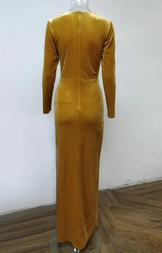 Full-length view of a woman in a dark pleated velvet V-neck long sleeve gown.