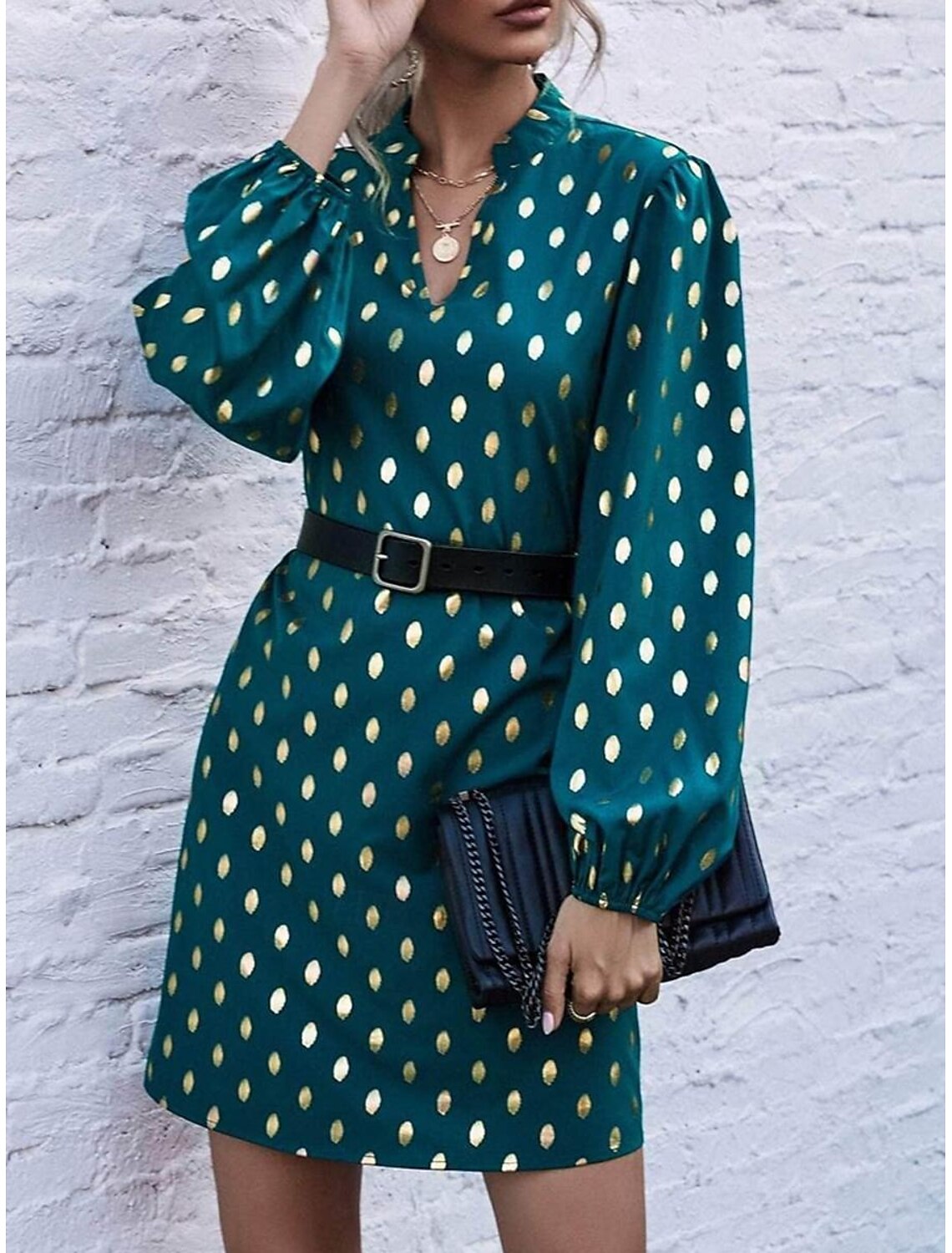 Woman wearing a black polka dot long sleeve mini dress with a notched neck.
