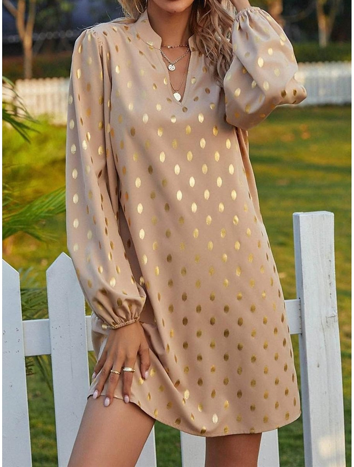 Close-up of the notched neckline and polka dot pattern on the mini dress.