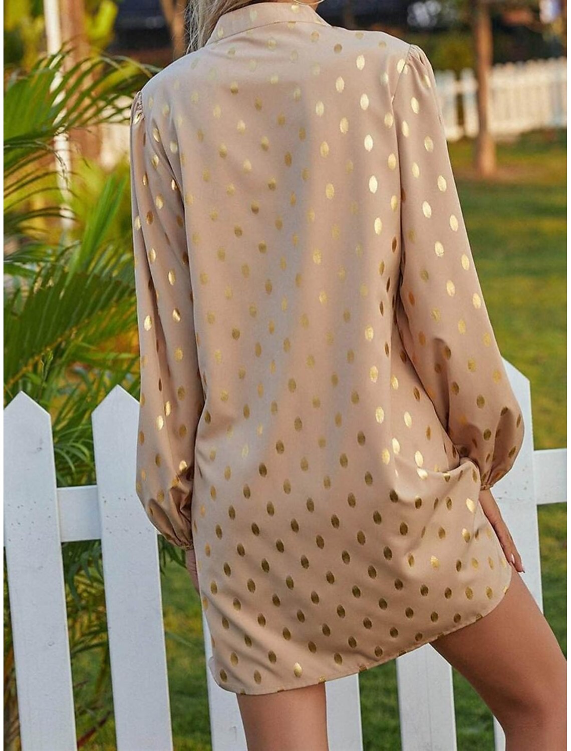Woman walking in a flowy polka dot long sleeve mini dress.