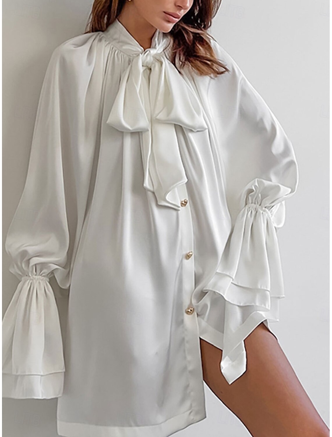 Woman wearing an elegant plain long sleeve shirt with a lace-up neck.