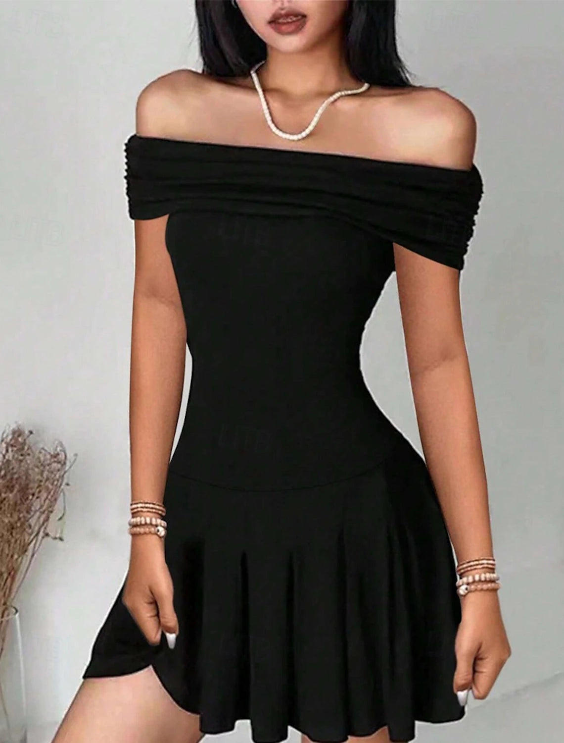 Woman posing in a black off-shoulder mini dress.