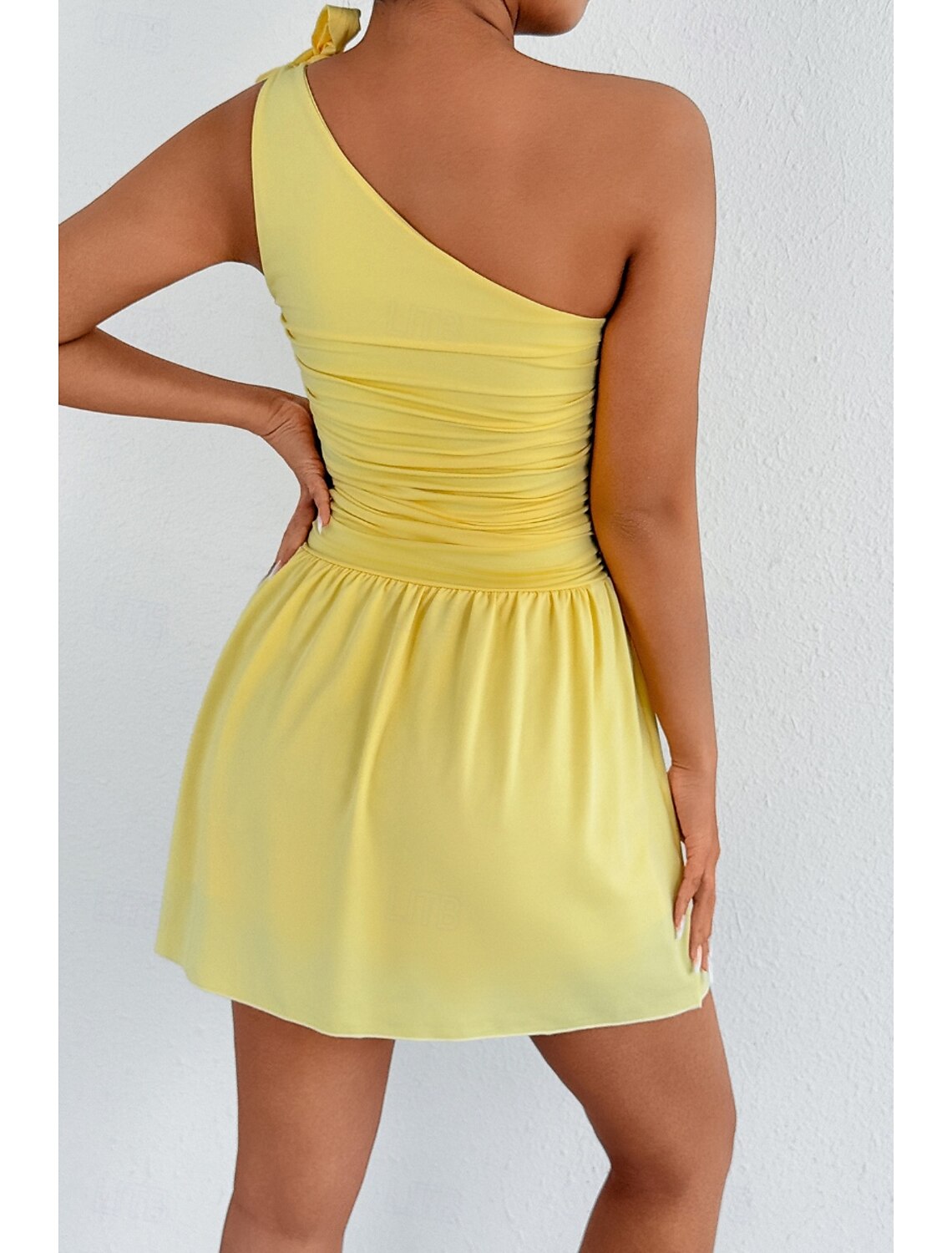 Back view of a model wearing a light yellow one-shoulder mini dress.