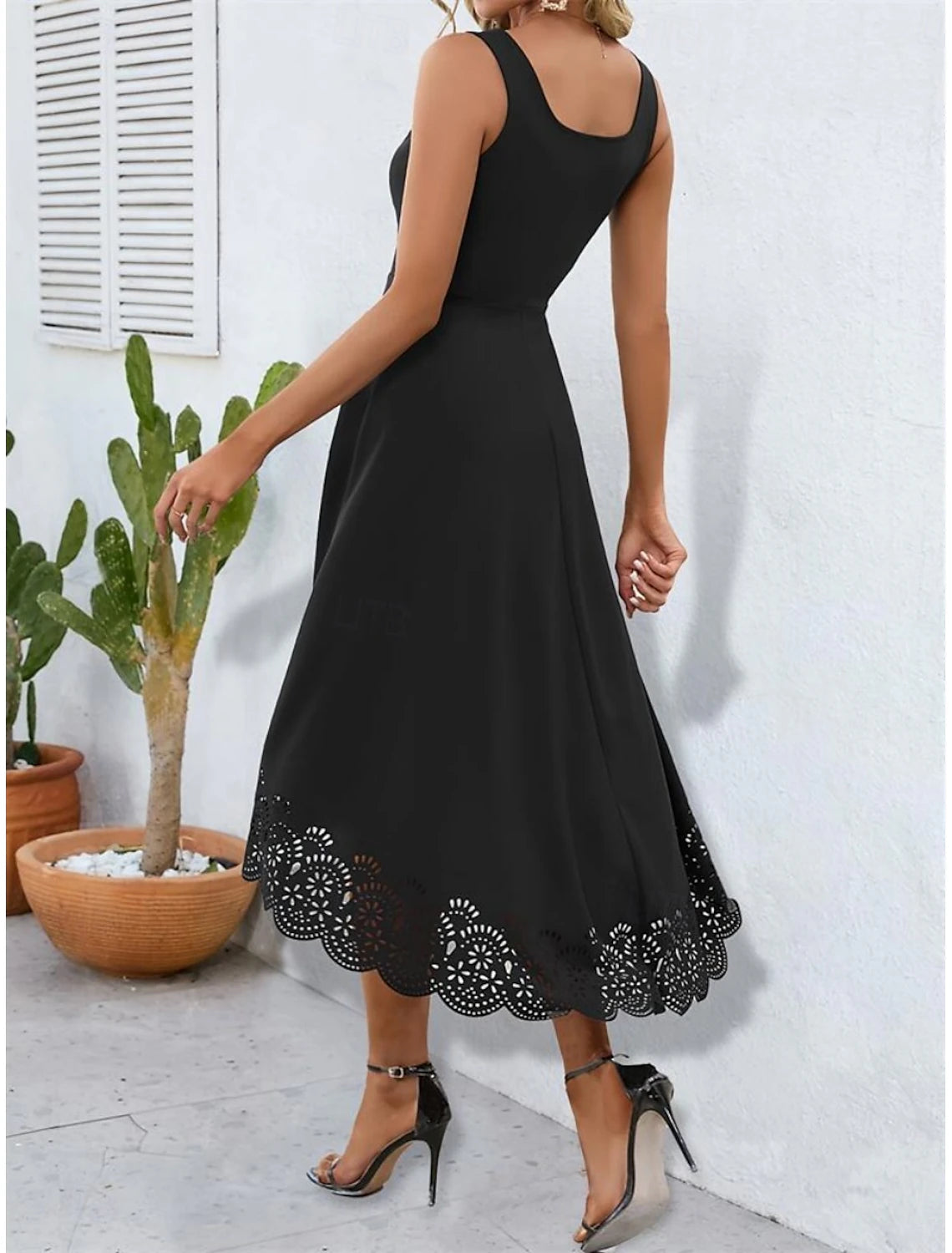 Back view of a model wearing an elegant black spaghetti strap dress.