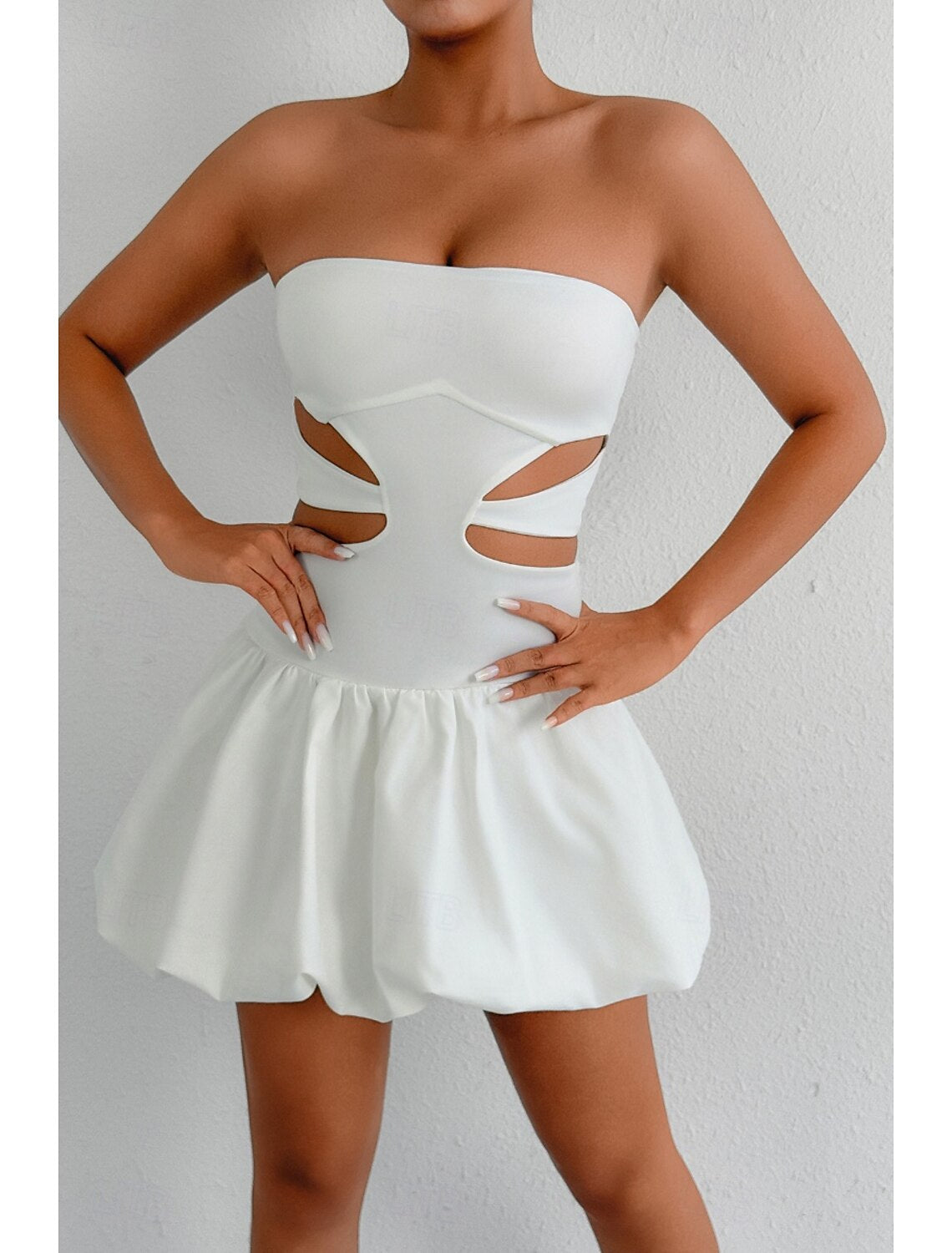 Woman posing in a white strapless mini dress, front view.