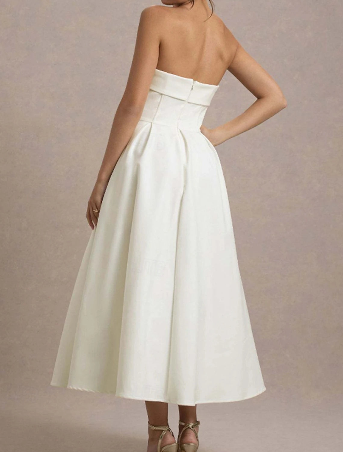 Back view of a woman wearing a white strapless party dress.