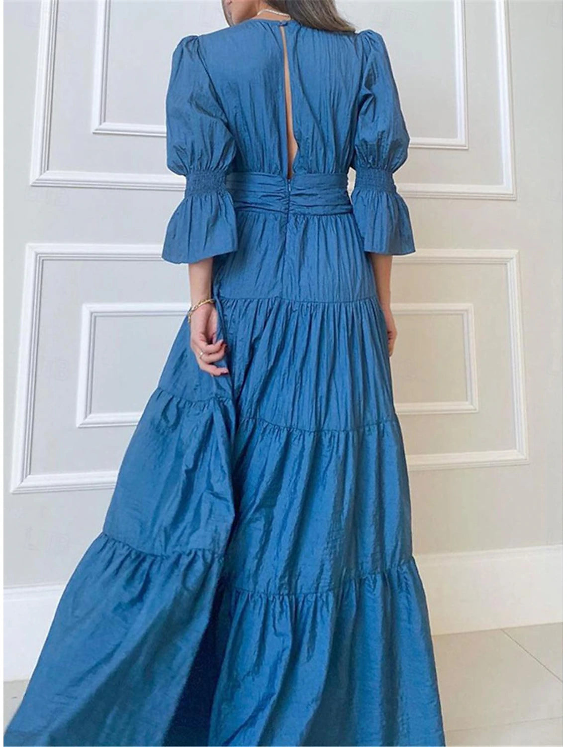 Back view of a woman in an elegant ruched A-line V-neck maxi dress, showcasing the flowing skirt.
