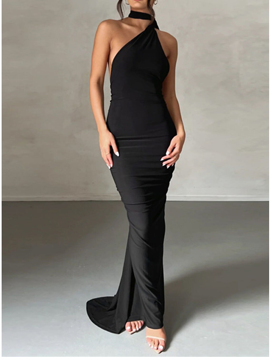Woman wearing a white ruched backless one-shoulder special occasion dress.