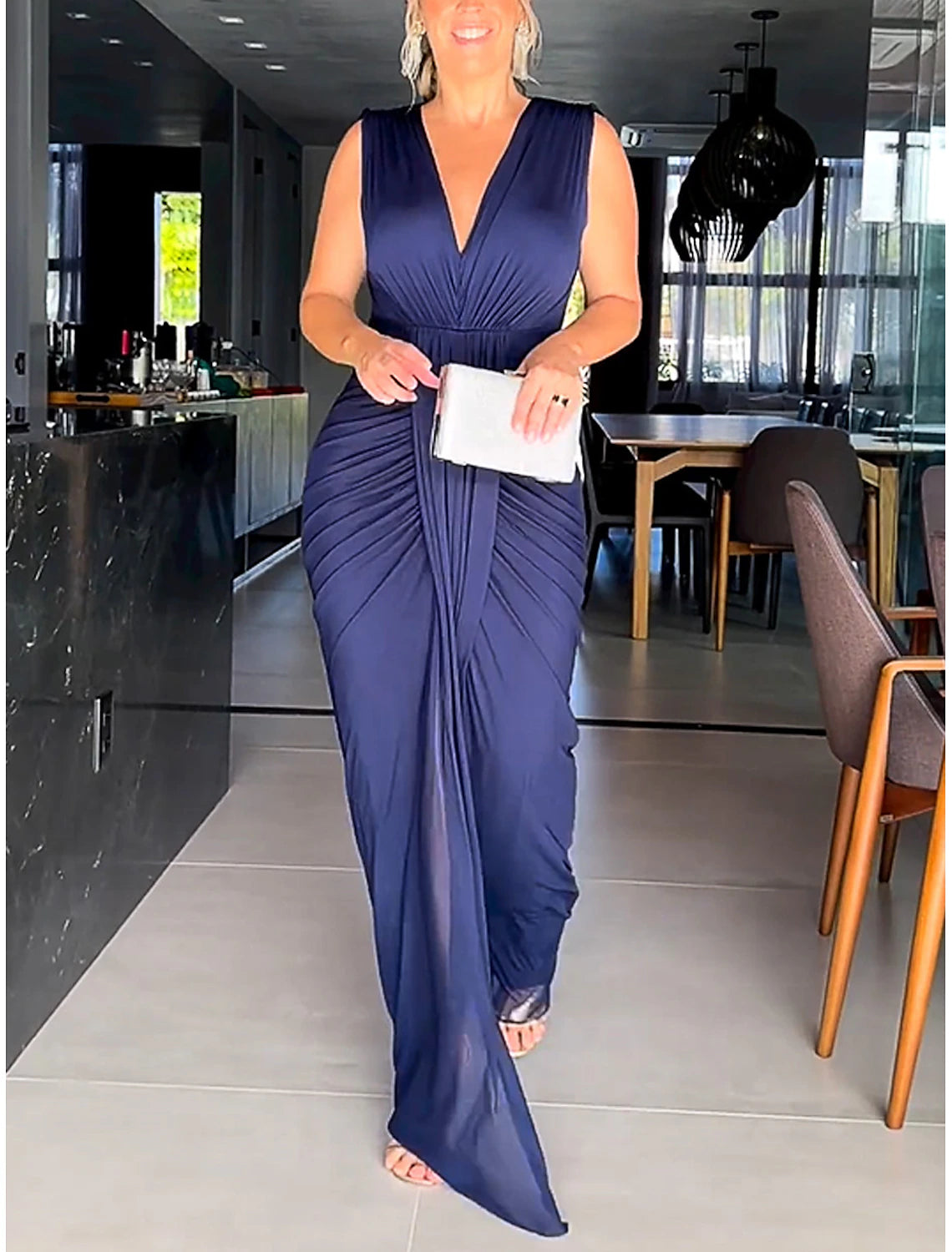 Woman wearing an elegant black ruched backless V-neck formal dress.