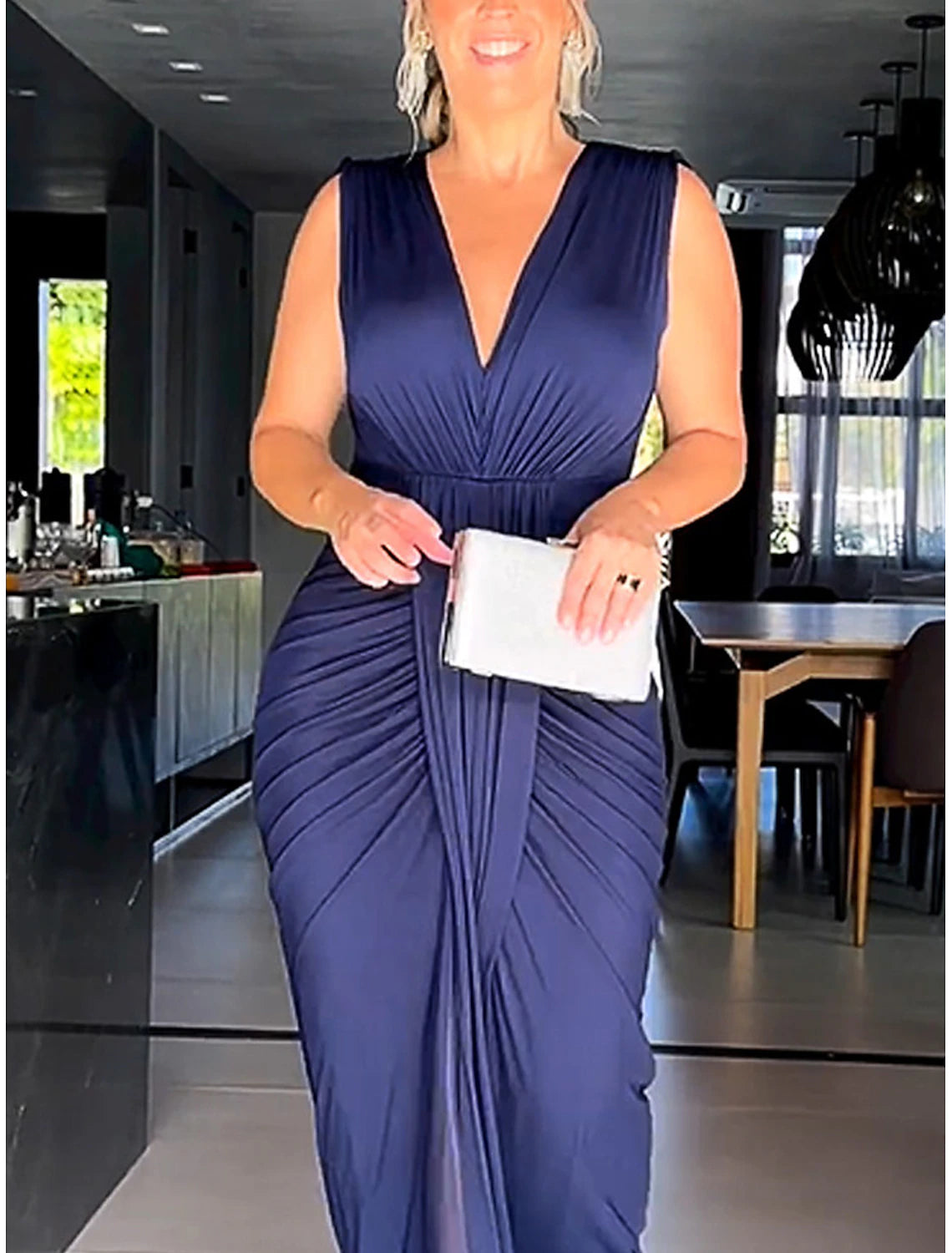 Woman posing gracefully in a black sleeveless V-neck party dress.
