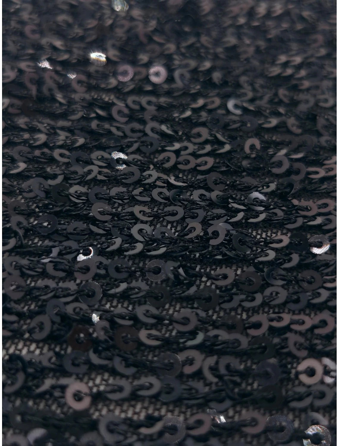 Close-up of the ruched fabric detail on the black mini dress.