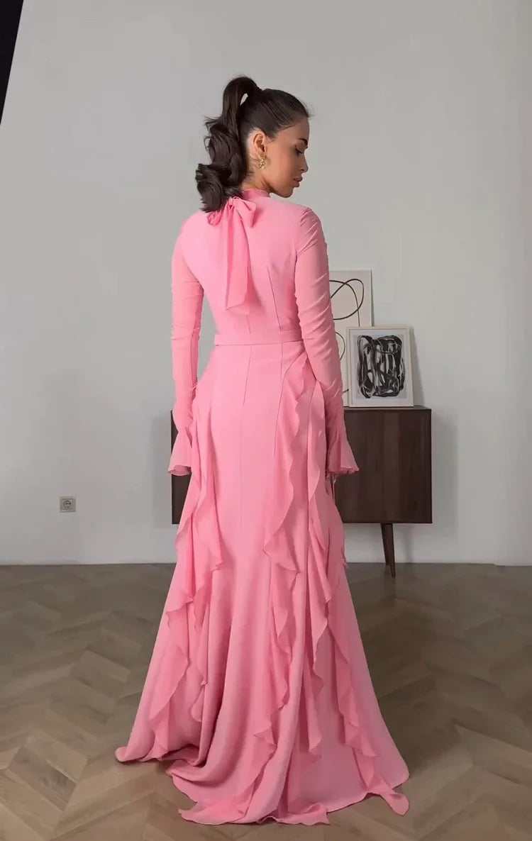 Model wearing a pink ruffle chiffon long sleeve dress, side view.