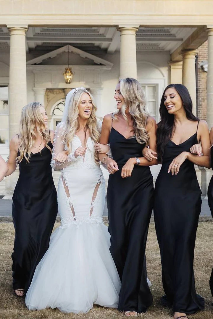 Woman wearing a black satin cowl neck spaghetti strap long bridesmaid dress.