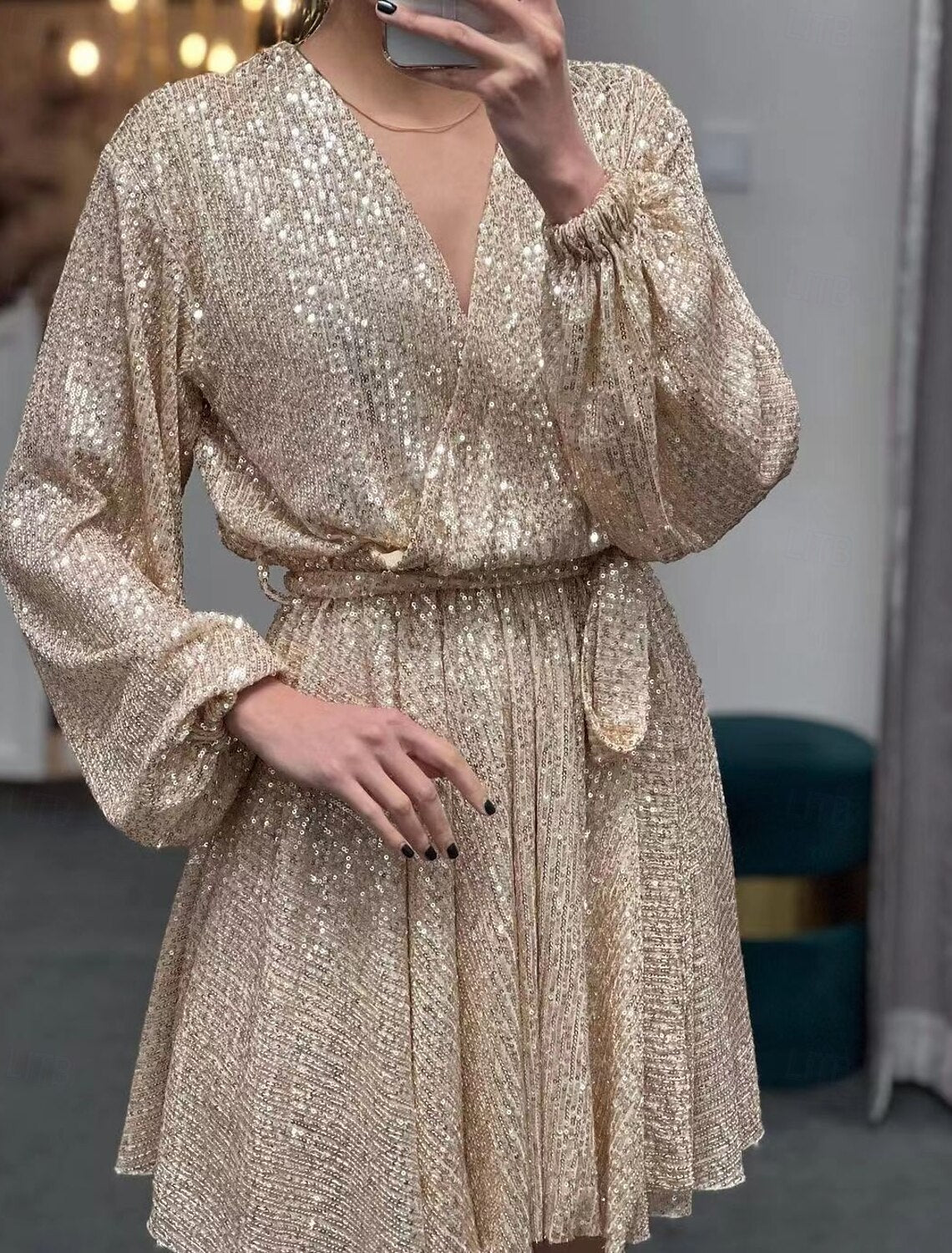 Woman wearing an elegant champagne sequin mini dress with long puff sleeves and a V-neck.