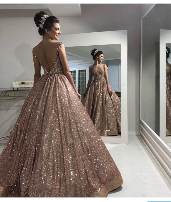 Woman wearing a champagne sequin long prom dress with a V-neckline.