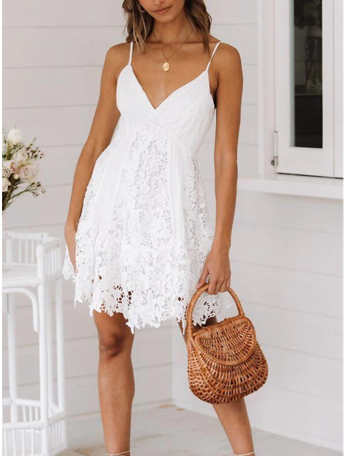 Woman posing in a white elegant sleeveless strap homecoming dress, highlighting the lace detail.