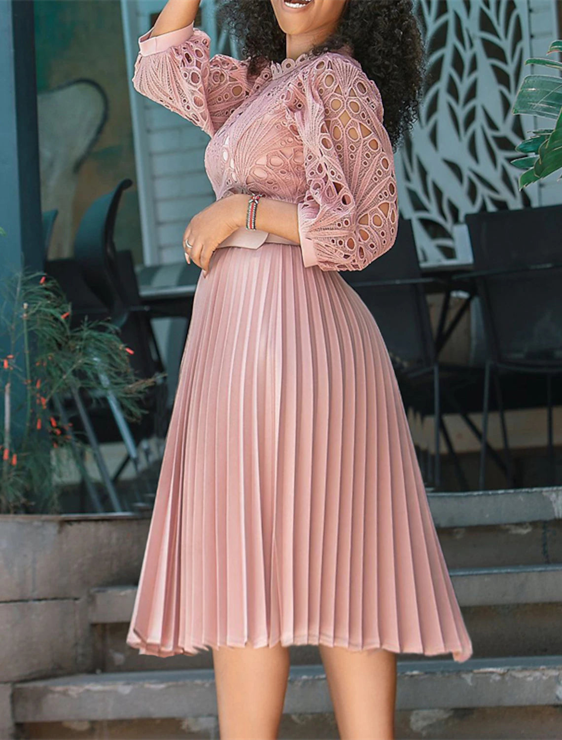 Woman wearing an elegant dark knee-length sheath dress, side view.
