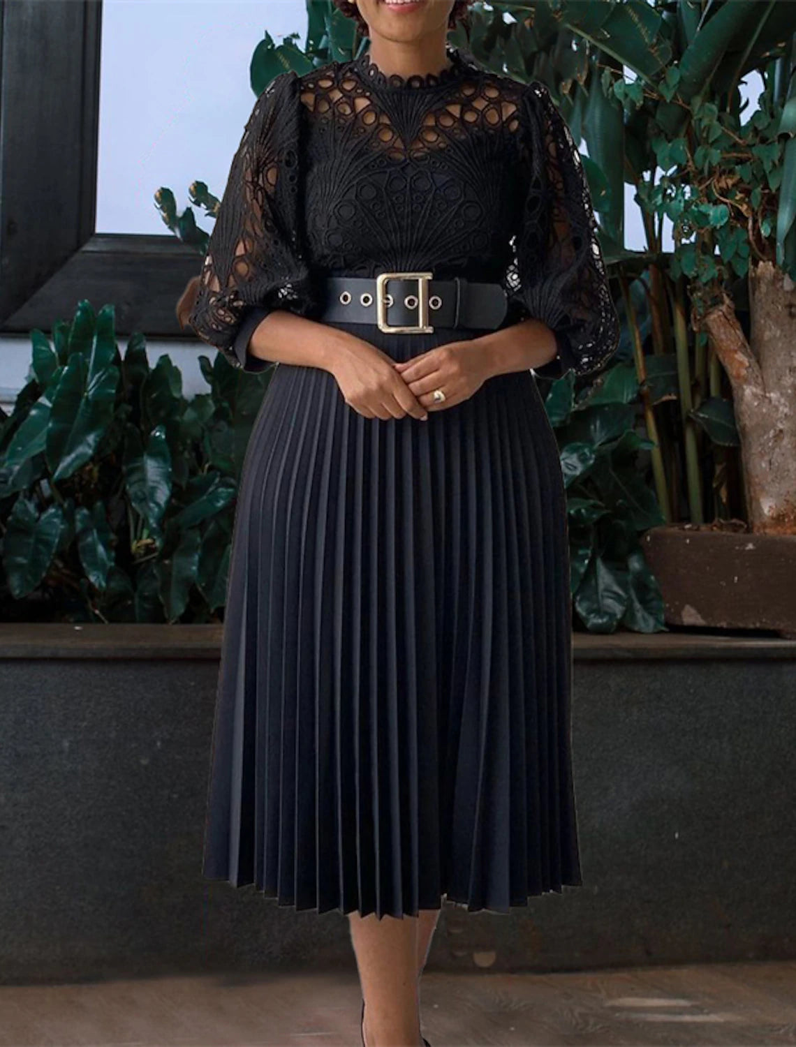 Woman wearing an elegant dark knee-length sheath dress, back view.
