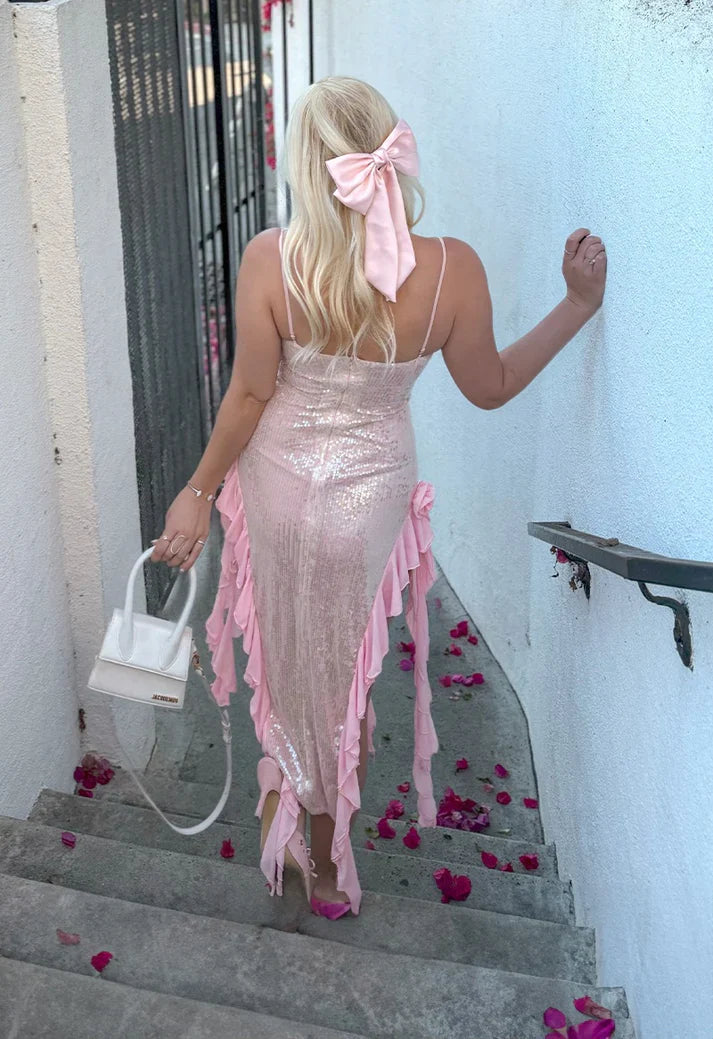 Model wearing a pink sequin sheath dress with spaghetti straps, side view.