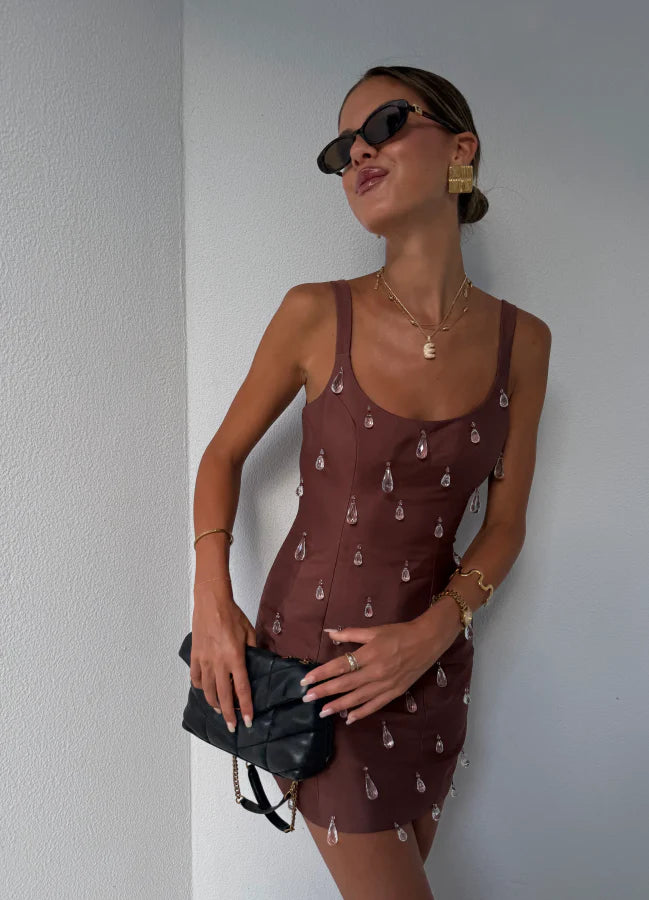 Close-up of the crystal strap detail on the brown satin dress.