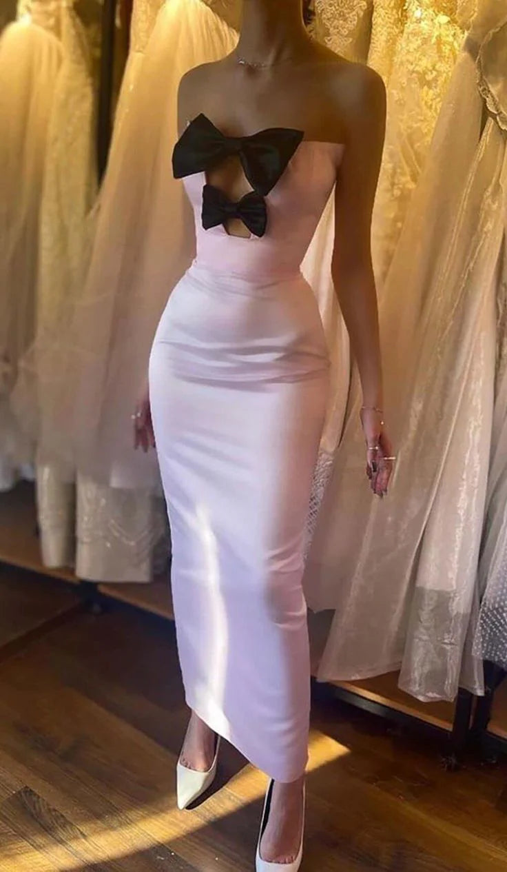 Woman wearing an elegant strapless sheath evening dress with a prominent bow-knot detail.
