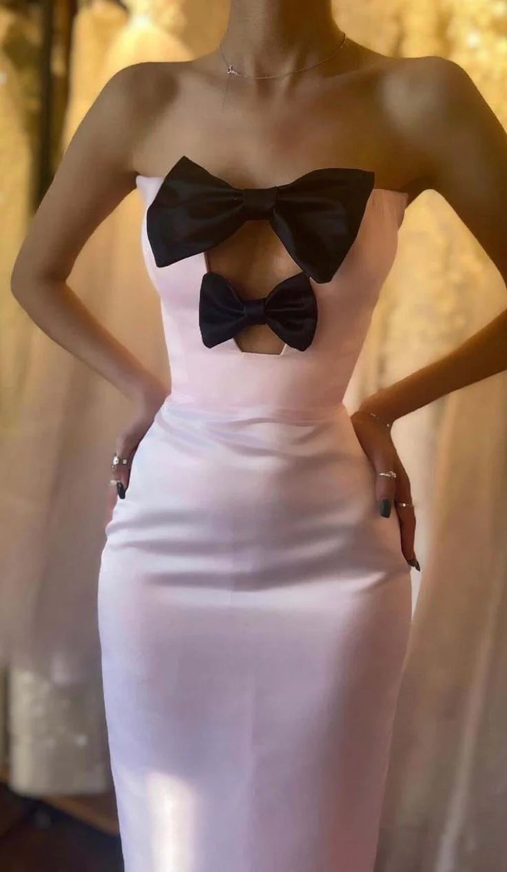 Full-length view of a woman in a sophisticated strapless formal gown featuring a bow-knot accent.